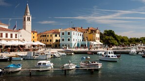 A marina with boats docked, a church with a bell tower, and colorful buildings along the waterfront. - Pool & Spa House Betiga 2 (Vodnjan)
