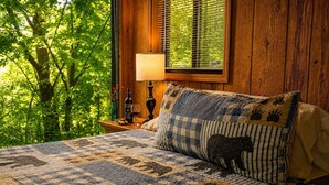 A bedroom with a bed, a nightstand, a lamp, and a window with blinds.