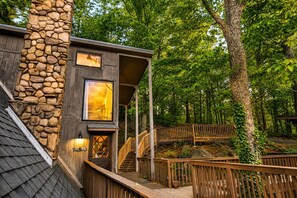A cabin with a stone exterior, wooden deck, and a staircase leading to the entrance. - Make Hallmark Memories! Cozy mountain cabin in the woods.  (Gatlinburg)