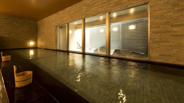 A spacious indoor area with a polished floor, wooden ceiling, and brick walls. - Village Kyoto (Kyoto)