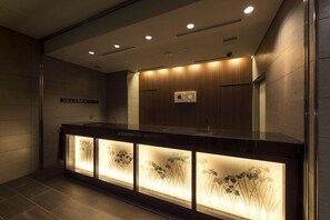 A modern bathroom with a wooden vanity, recessed lighting, and a sign reading "VILLAAGE KYOTO".