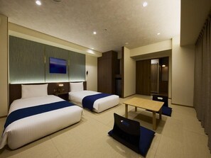 A hotel room with two beds, a desk, and a mirror.