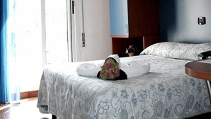 A bedroom with a bed, a wooden headboard, a window with curtains, and a door. - Hotel Trifoglio (Jesolo)