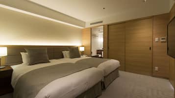 A hotel room with a large bed, two bedside tables, a nightstand, a wall-mounted TV, and a wooden wardrobe.