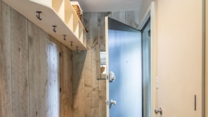 A narrow hallway with wooden walls, a bench, and a blue door.