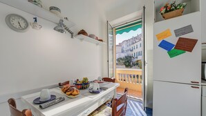 Una cocina con una mesa, sillas, un refrigerador y una ventana con vistas a edificios.