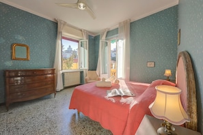 A bedroom with a bed, a dresser, a lamp, and a window with curtains.