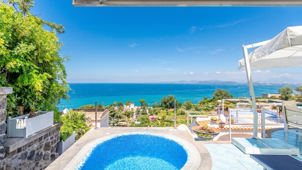 A swimming pool with a view of the sea, a covered area, and a stone wall. - Dependance Castiglione With Pool And View (Casamicciola Terme)