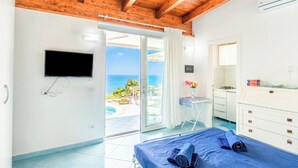 A bedroom with a bed, a TV, a desk, and a view of the sea. - Dependance Castiglione With Pool And View (Casamicciola Terme)