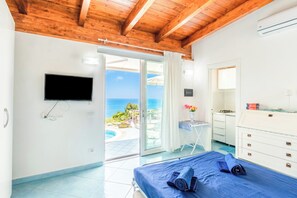 Ein Schlafzimmer mit Bett, Fernseher, Schreibtisch und Meerblick.