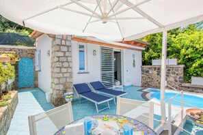 Ein Poolbereich mit Liegestühlen, einer überdachten Sitzgelegenheit und einem Pool.