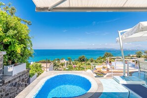 Ein Swimmingpool mit Meerblick, einem überdachten Bereich und einer Steinmauer.