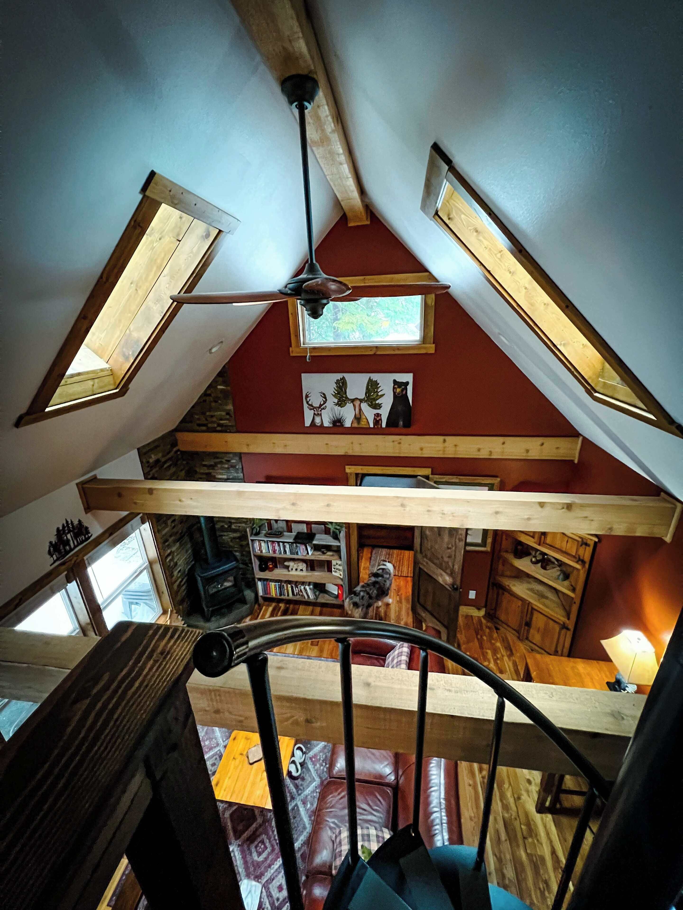 Une pièce de style « loft », avec des plafonds inclinés, des poutres en bois et des fenêtres de toit.