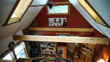 Une pièce de style « loft », avec des plafonds inclinés, des poutres en bois et des fenêtres de toit.