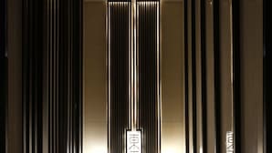 A modern hallway with vertical light strips and a reflective floor, leading to a central door with illuminated signage. - Xi'an Eastern House Boutique Hotel (Xi'an)