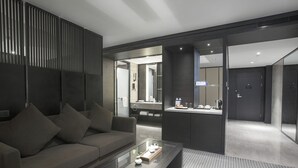 A modern hotel room with a sofa, a glass coffee table, and a bathroom visible through a glass partition. - Xi'an Eastern House Boutique Hotel (Xi'an)