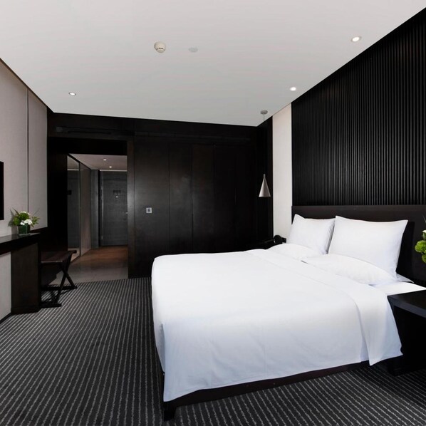 A modern hotel room with a large bed, a desk, and a dark accent wall.