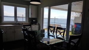 Une cuisine donnant sur un lac, un coin repas avec des chaises et une table, et une grande fenêtre.