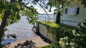 Une propriété située au bord de l’eau, dotée d’un mur de soutènement en béton, d’une chaise et d’une maison avec des fenêtres.