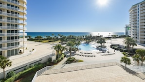 A resort with a pool, palm trees, and a view of the ocean.
