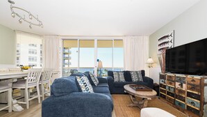 A living room with a sofa, TV, and a dining area with a table and chairs.