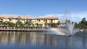 Hotel à beira-mar com uma fonte, edifícios refletidos e céu limpo.