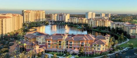 A hotel complex with multiple buildings, a central courtyard, and a body of water.
