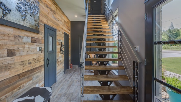 Un escalier en bois avec une rampe en métal, menant à une porte portant l’inscription « PRESIDIO ».