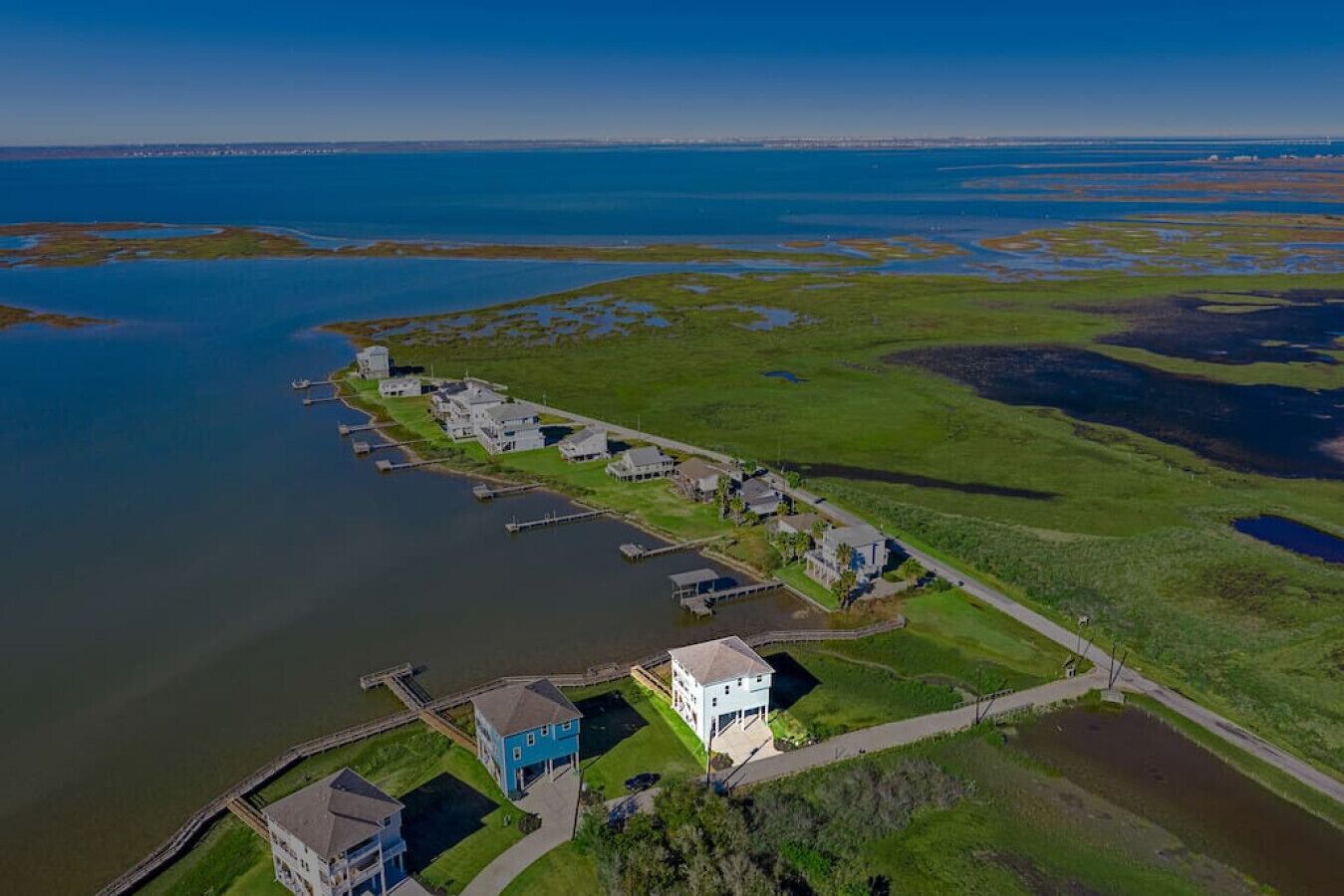 An aerial view of a coastal property with a marina, houses, and a large body of water.