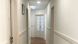 A hallway with wooden flooring, white walls, and a door at the end. - Green View Home (Lisbon)
