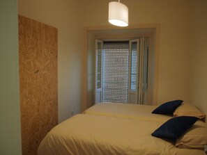 Una camera da letto con un letto, cuscini, una lampada a soffitto e una porta con una finestra.