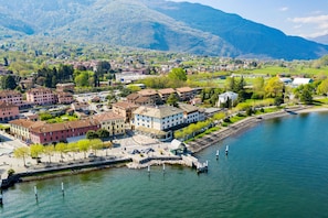 A riverside town with buildings, a dock, and a mountainous backdrop. - Margherita (Colico)