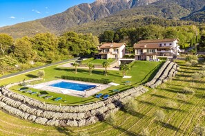 A resort with a swimming pool, multiple villas, and a mountainous backdrop. - Margherita (Colico)