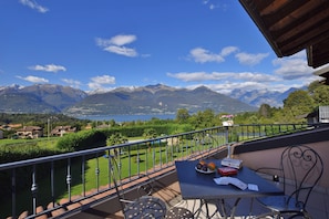 Un balcón con mesa, sillas y vistas a montañas y un lago.