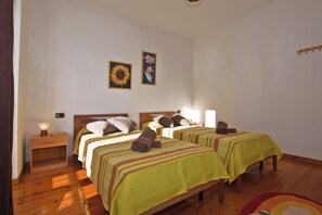 Una habitación con dos camas, una mesita de noche, una mesa y una pared con dos cuadros.
