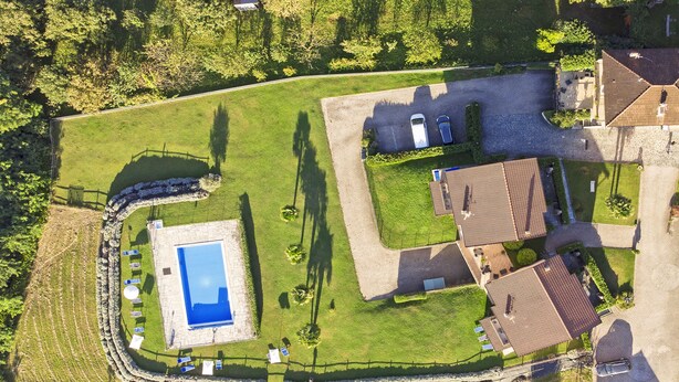 An aerial view of a residential area with a swimming pool, a fenced garden, and a house with a tiled roof. - Iris (Colico)
