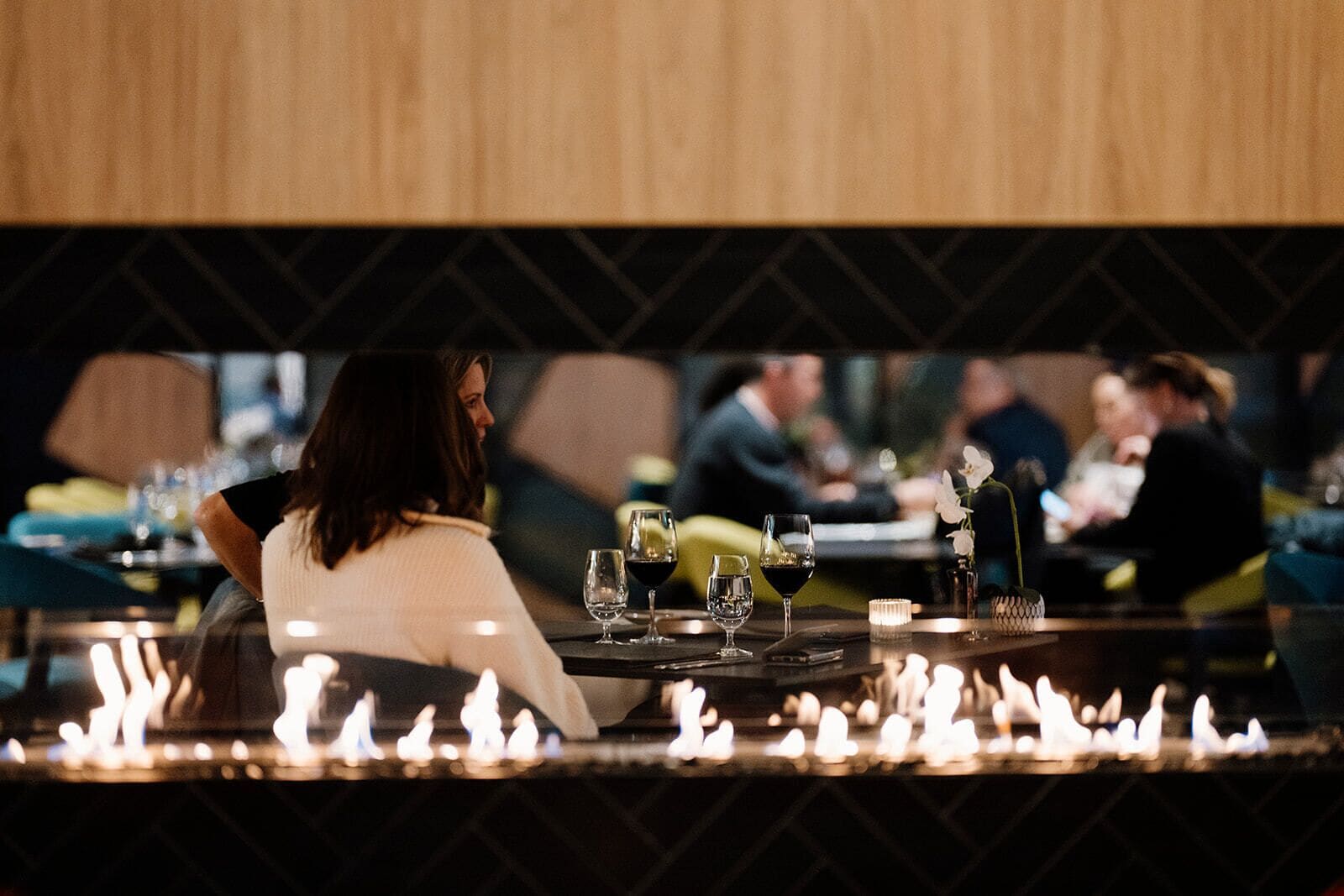 Un ristorante con tavoli apparecchiati per mangiare, un elemento decorativo a forma di fuoco in primo piano e un muro decorato sullo sfondo.