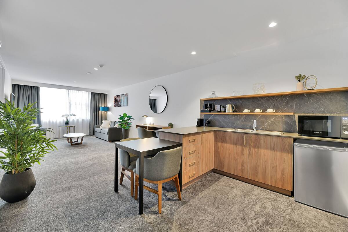 A modern kitchen with a dining area, a large potted plant, and a built-in microwave.