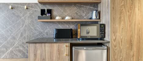 Una cocina compacta con un microondas Breville, un lavavajillas Hisense y un mueble de madera con salpicadero de mármol.