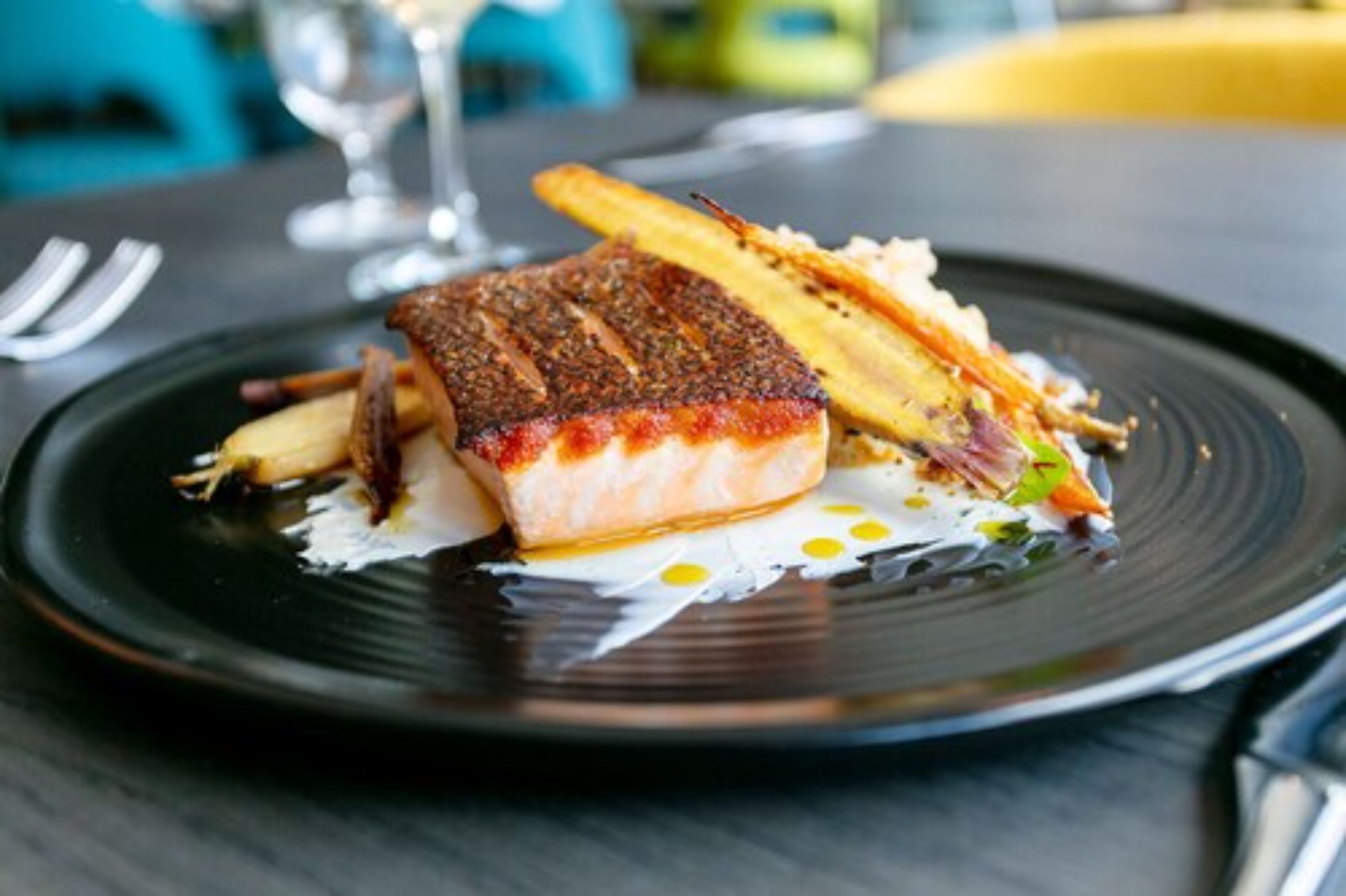 A plate with a piece of fish, some fries, and a small salad.