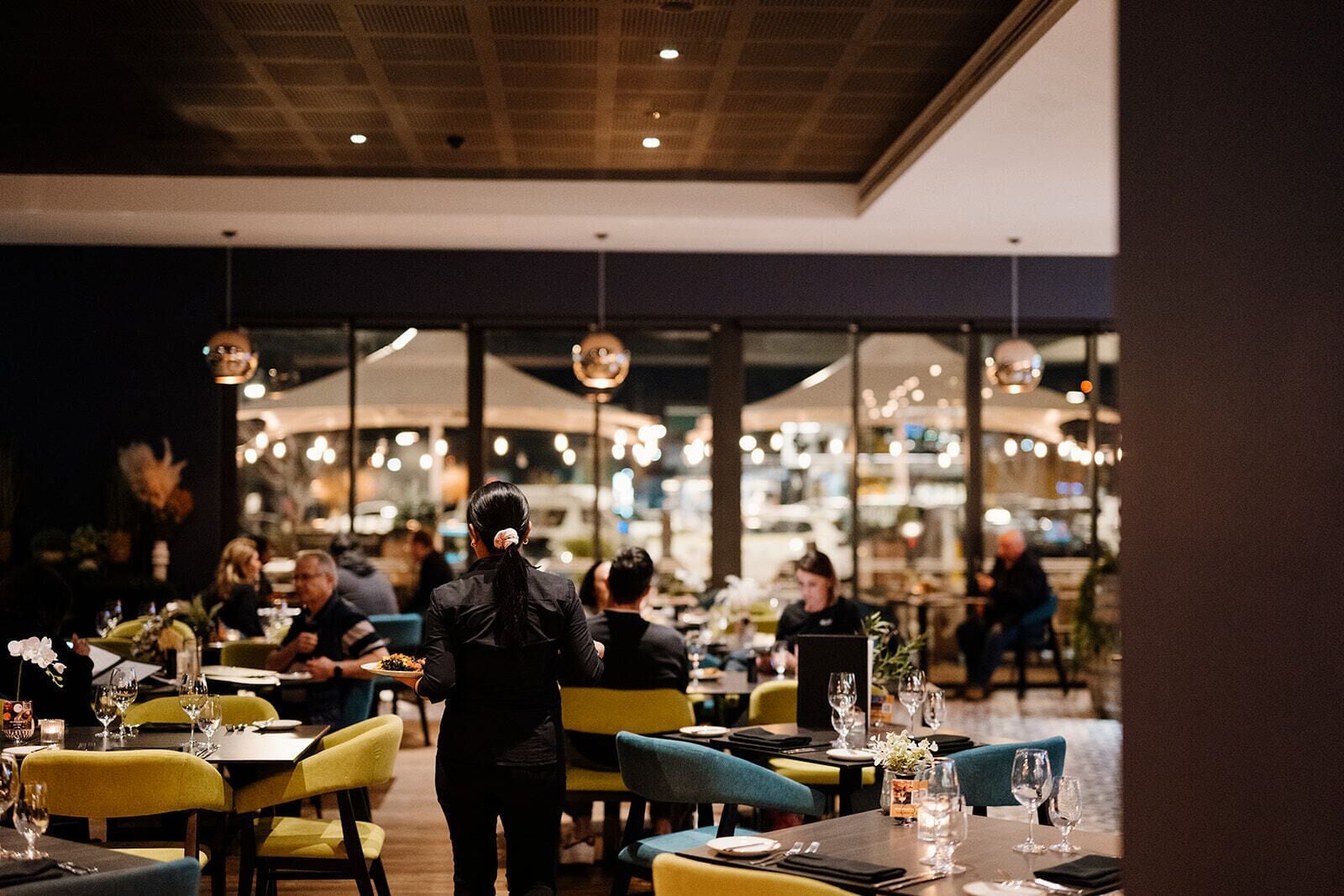 Ein Restaurantinneres mit Tischen, Stühlen und einem Kellner, der an den Tischen steht.
