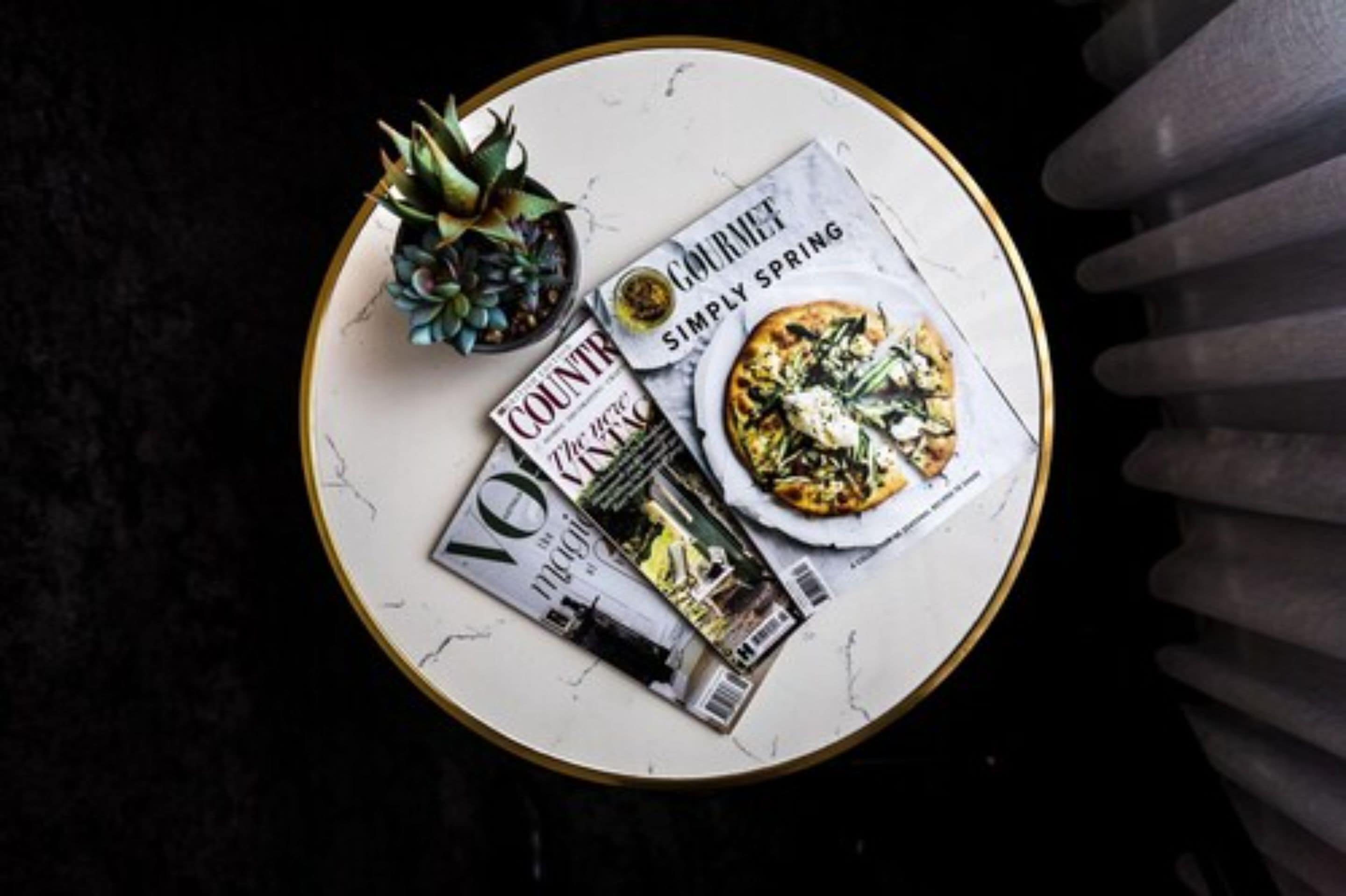 A round table with a magazine, a pineapple, and a plate of food.