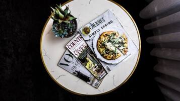 A round table with a magazine, a pineapple, and a plate of food.
