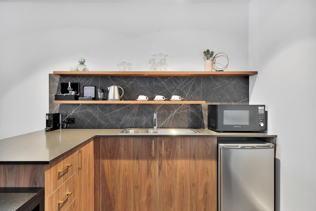 A modern kitchen with a built-in microwave, a stainless steel refrigerator, and a wooden cabinet with drawers.