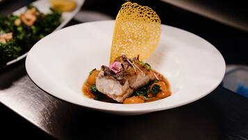 Une assiette contenant un plat composé d’une portion de viande, de légumes et d’un élément décoratif.