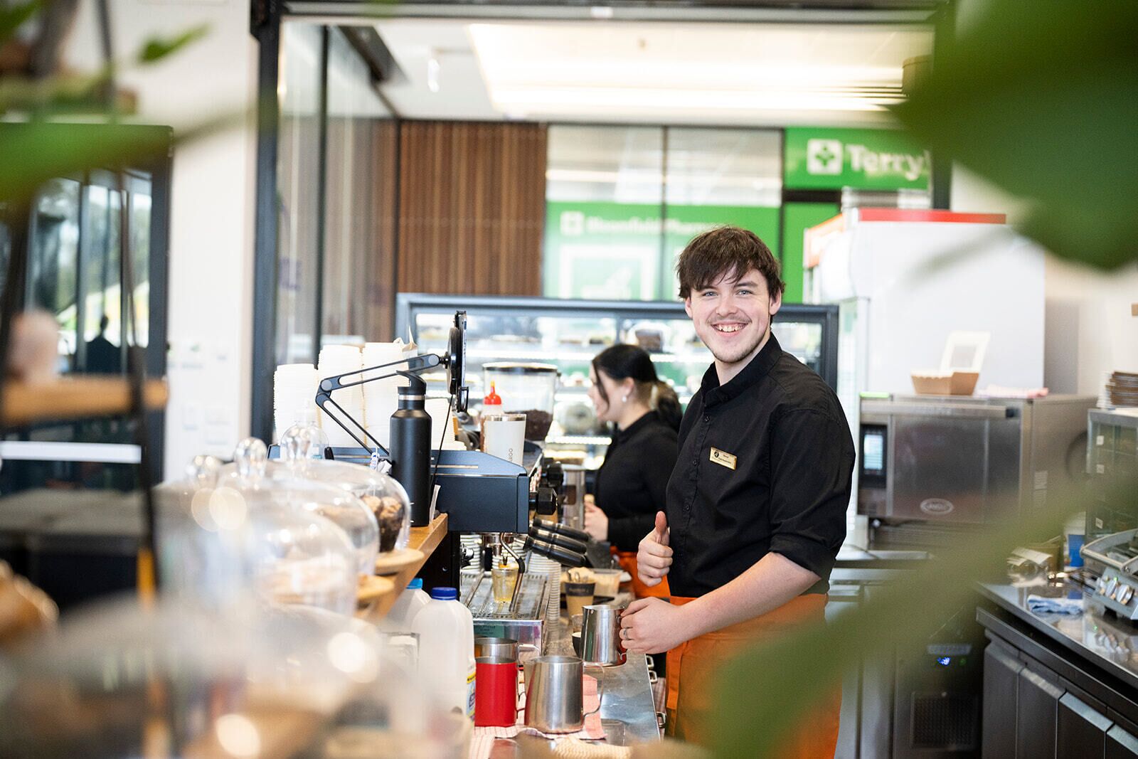 Un barista trabajando en una cafetería, con equipo para preparar café y un menú de fondo.