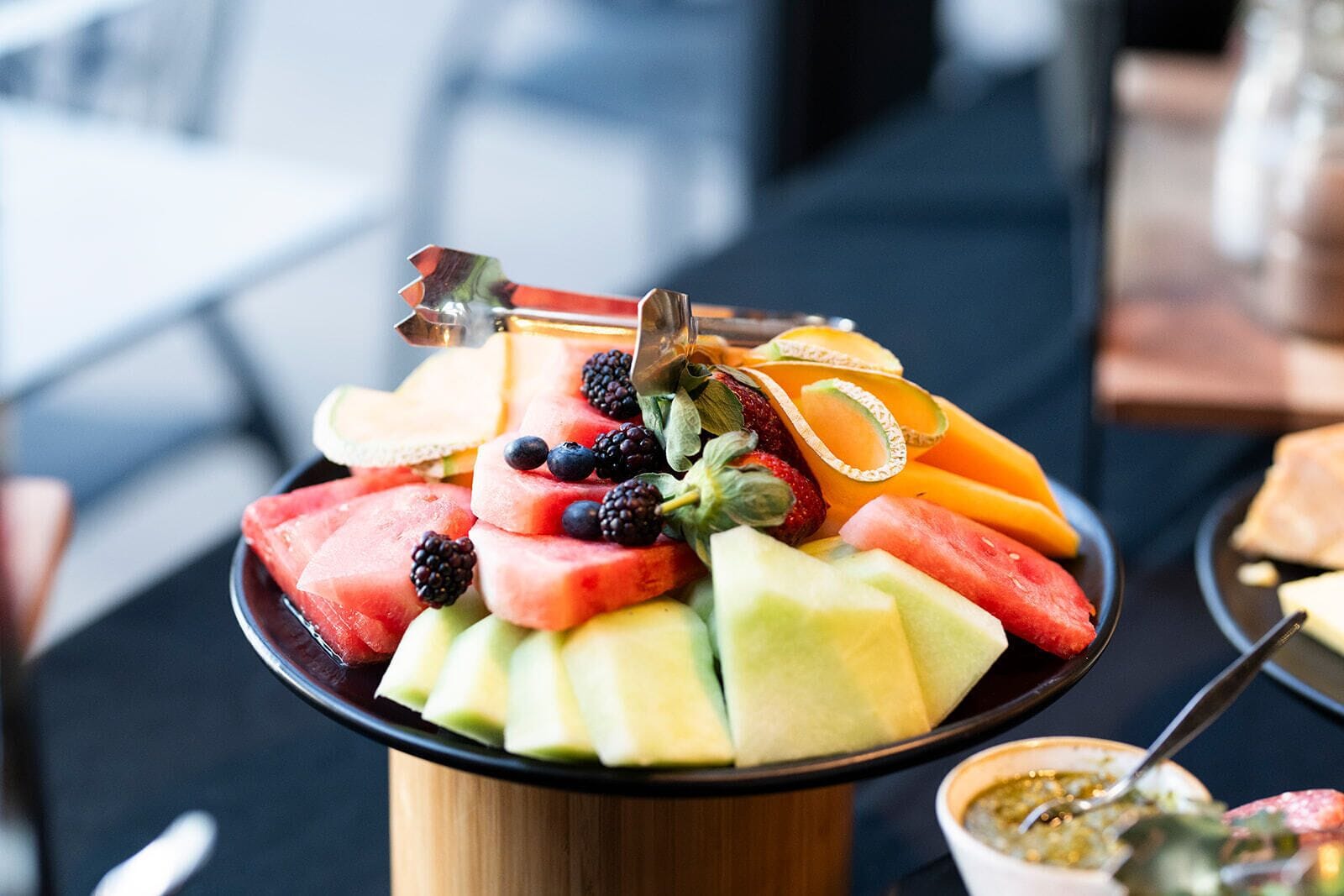 Una bandeja de frutas con sandía, melón, fresas, zarzamoras y naranjas.