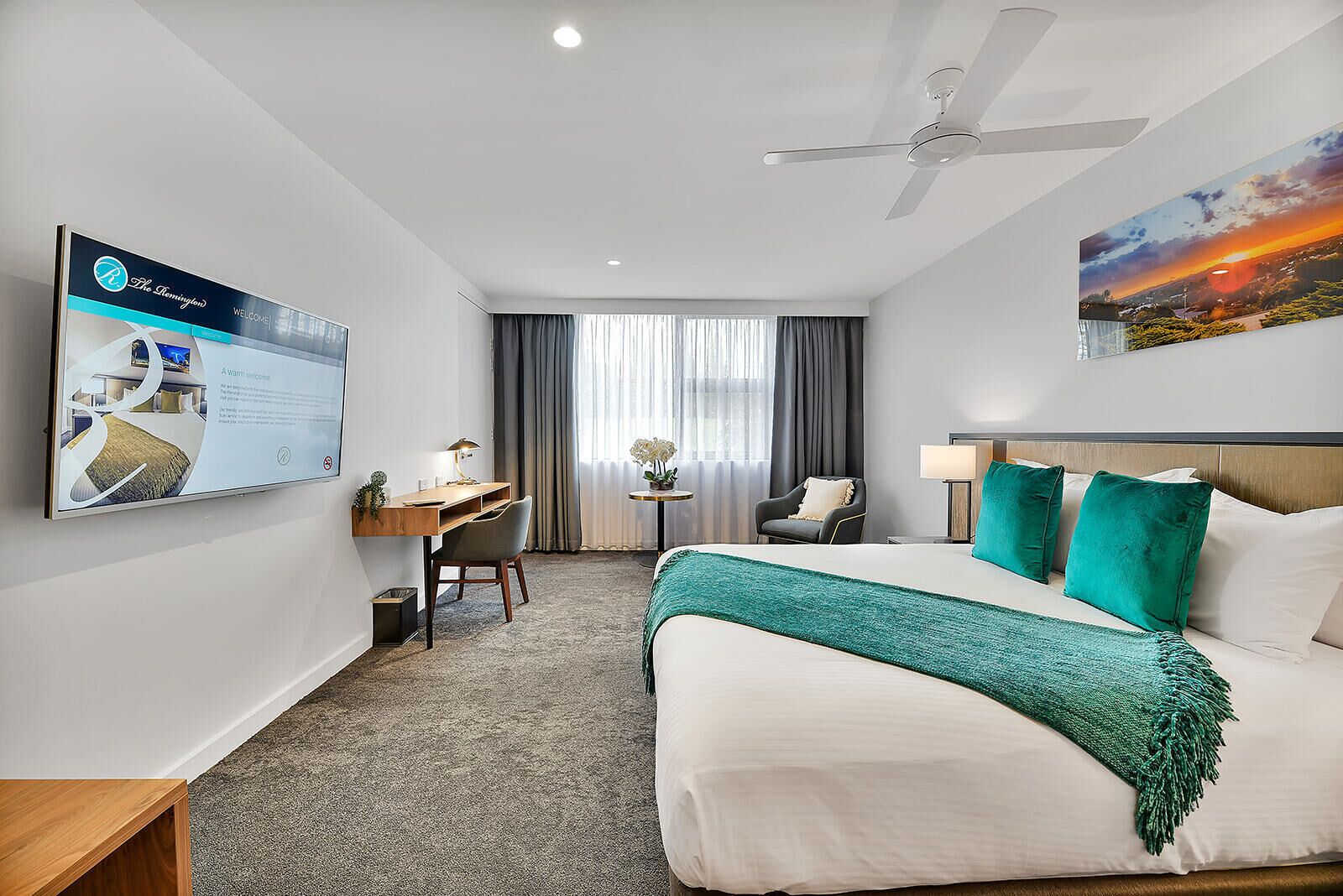 Une chambre d’hôtel équipée d’un lit, d’un bureau, d’une chaise et d’un ventilateur de plafond.