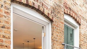 A brick exterior with a white-framed door leading into a modern kitchen with bar stools. - Private Historic Coach House Wicker Park (Chicago)