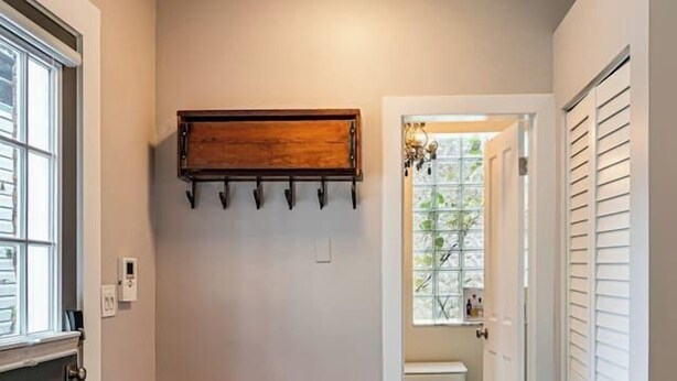 A hallway with a bench, a coat rack, and a door leading to another room. - Private Historic Coach House Wicker Park (Chicago)